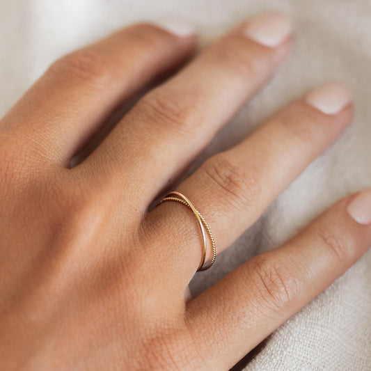 Two solid gold ring set stacked on model’s hand in criss cross design