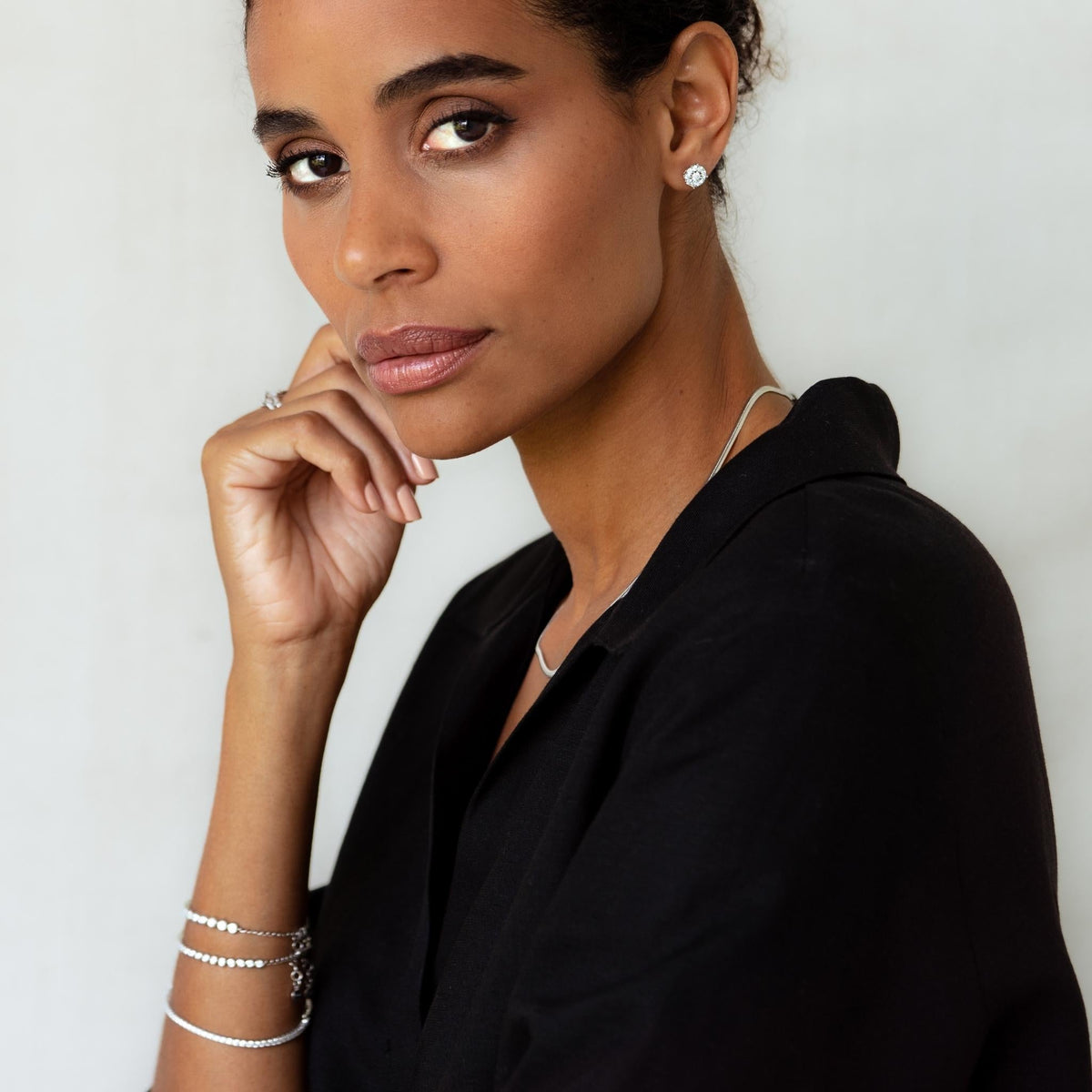 Close-up of a woman wearing Diamond Earrings - 2 Carat Miracle Plate styled with a black blouse on a neutral background
