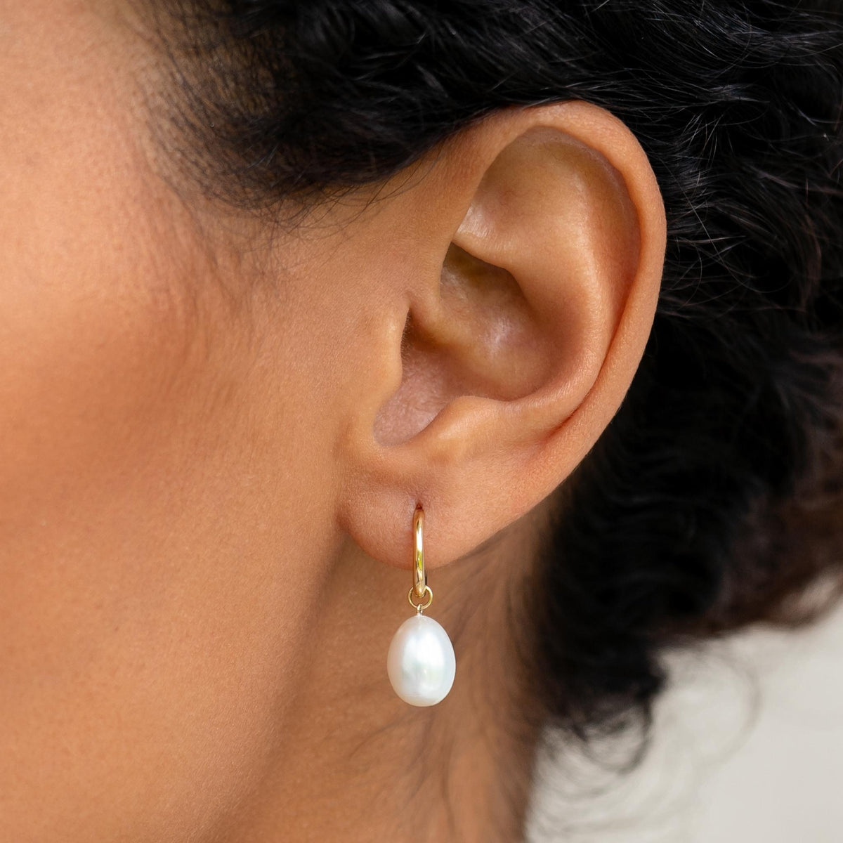 White freshwater pearl hoop earrings in 14k gold on model