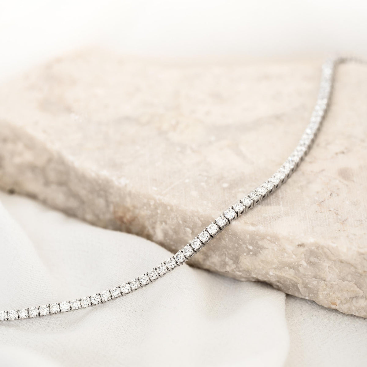 Diamond Tennis Bracelet 14k White Gold (2.6 - 2.7 ct tw, 6.5 inches) laid on a textured stone surface