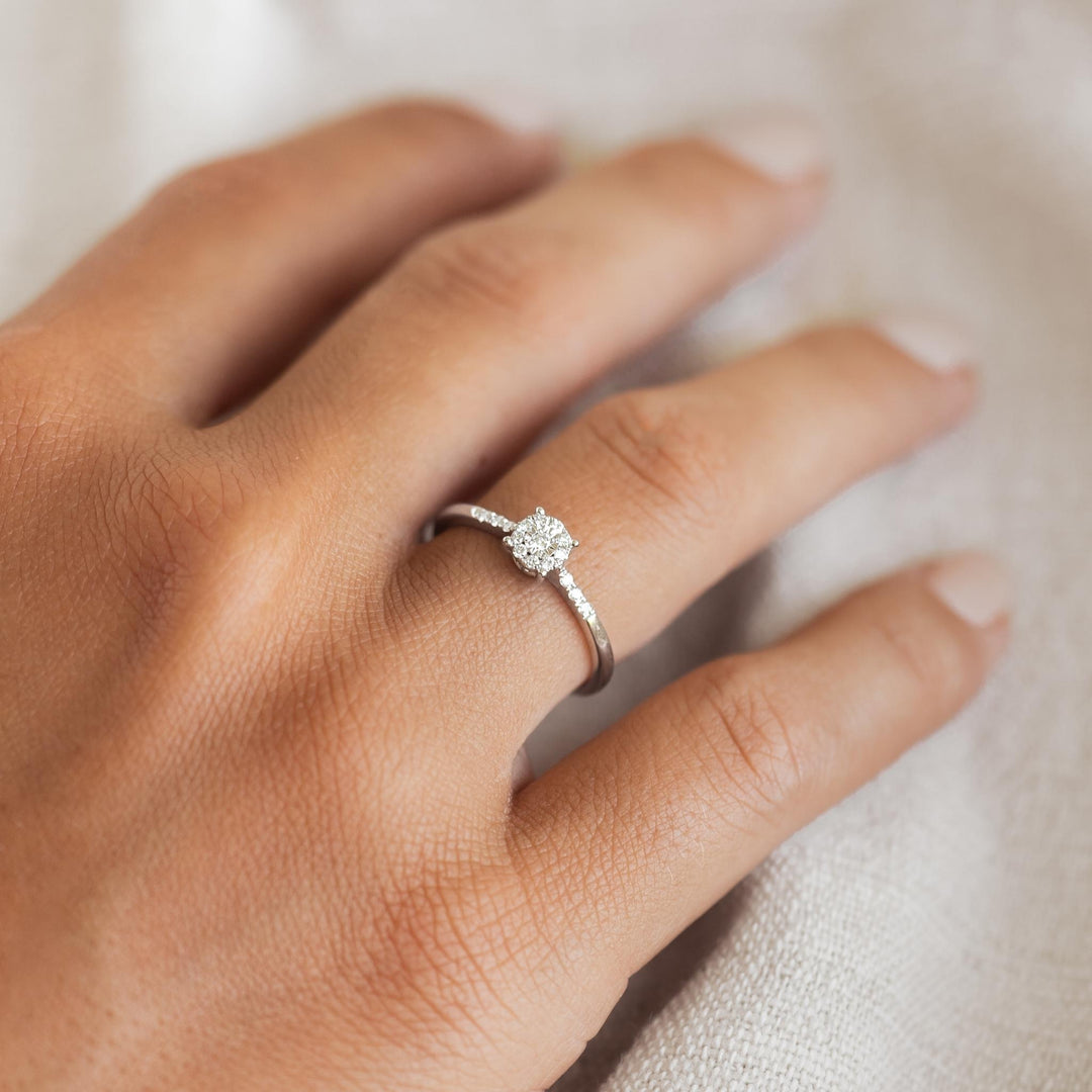 Close-up of hand wearing Round Cluster Diamond Ring White Gold - Zaira with sparkling diamonds on 14k white gold band