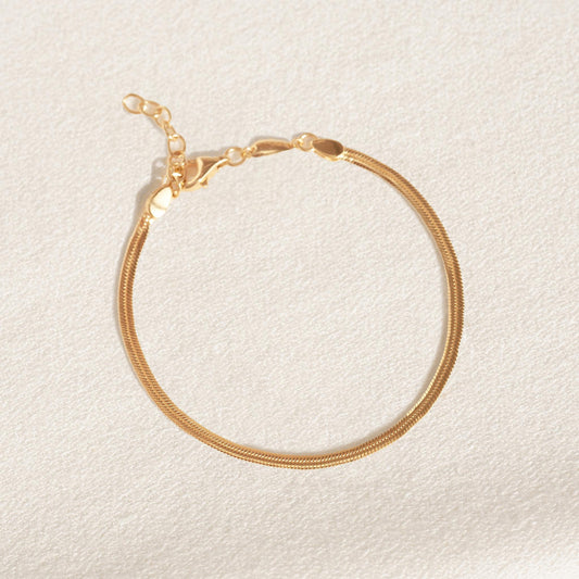 Gold vermeil snake chain bracelet displayed flat on a light textured background with adjustable clasp visible