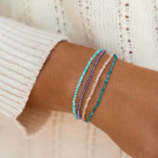 Close-up of a wrist wearing a Multi Strand Beaded Bracelet with amethyst, amazonite, sunstone, and apatite crystals