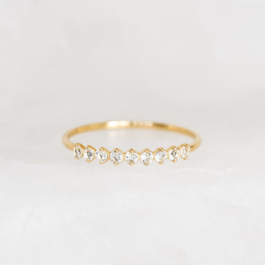 April Birthstone Ring 14k Gold - White Topaz with nine sparkling white topaz stones on a thin gold band on a neutral background