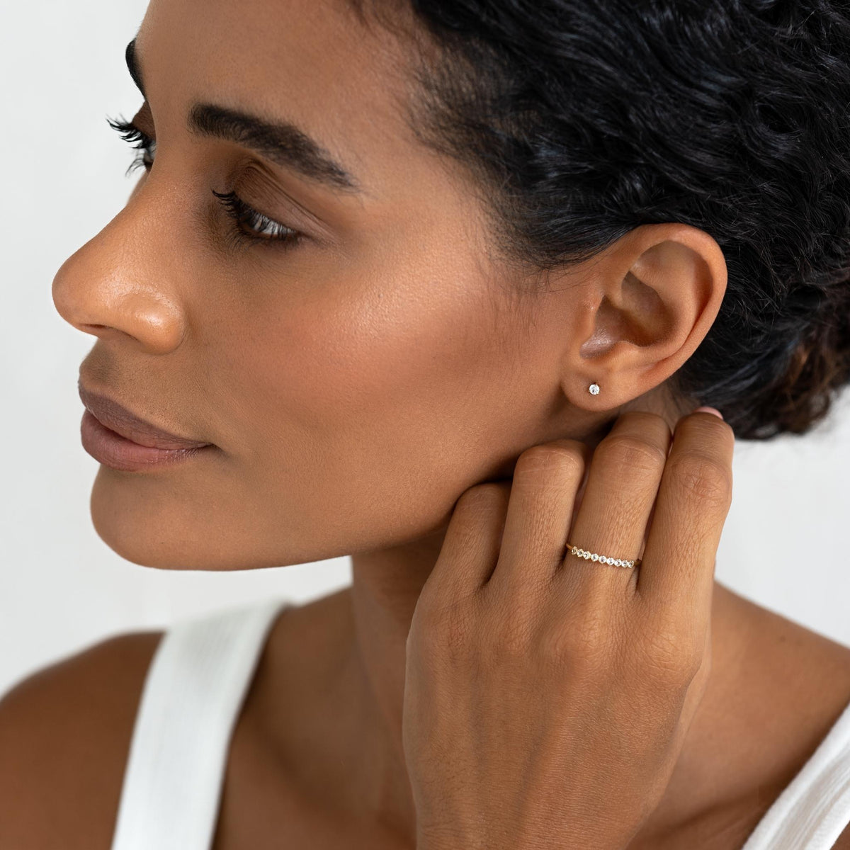 Close-up of woman wearing April Birthstone Ring 14k Gold - White Topaz with a white sleeveless top on a light background