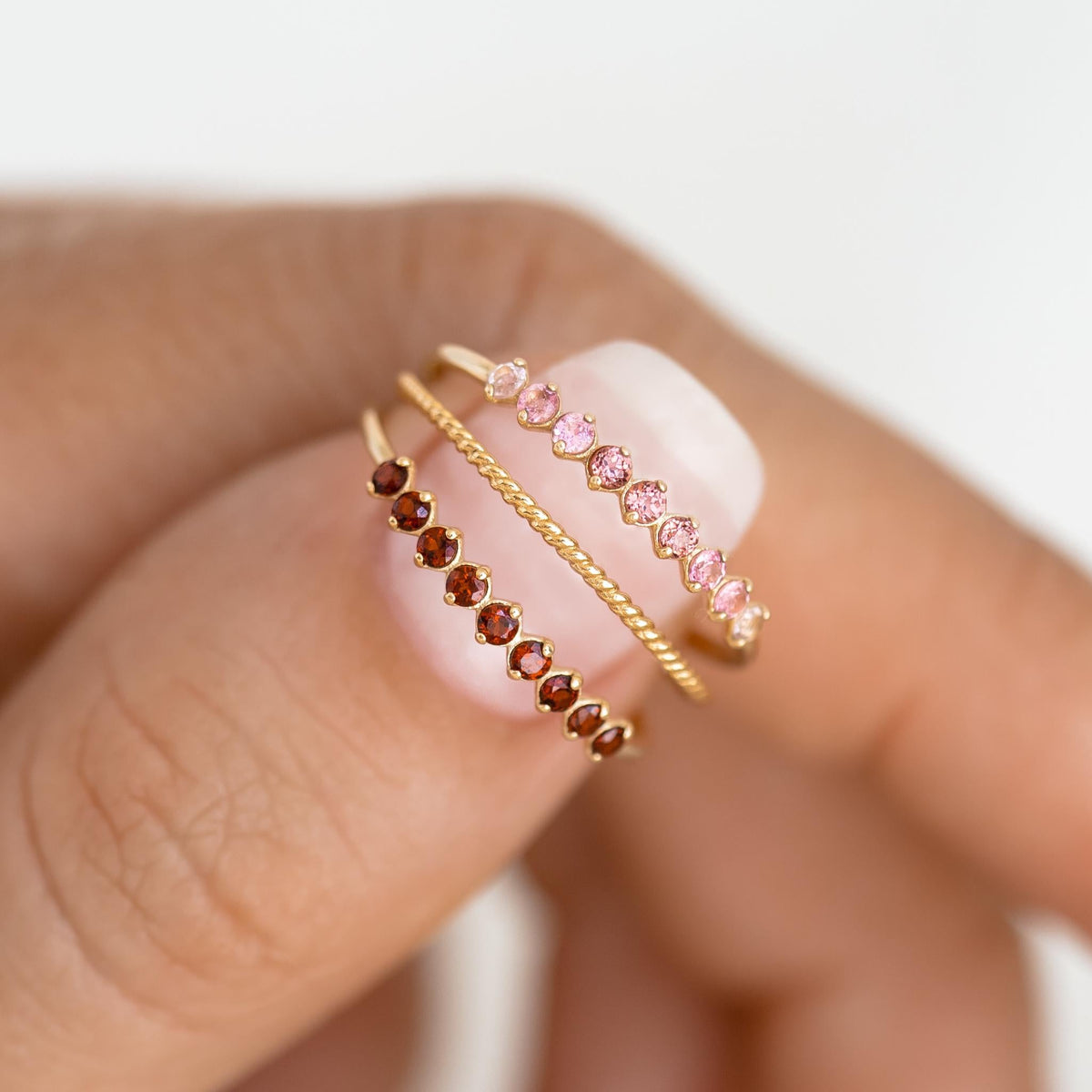 Close-up of hand wearing the January Birthstone Ring 14k Gold - Garnet with small deep red gemstones on a gold band