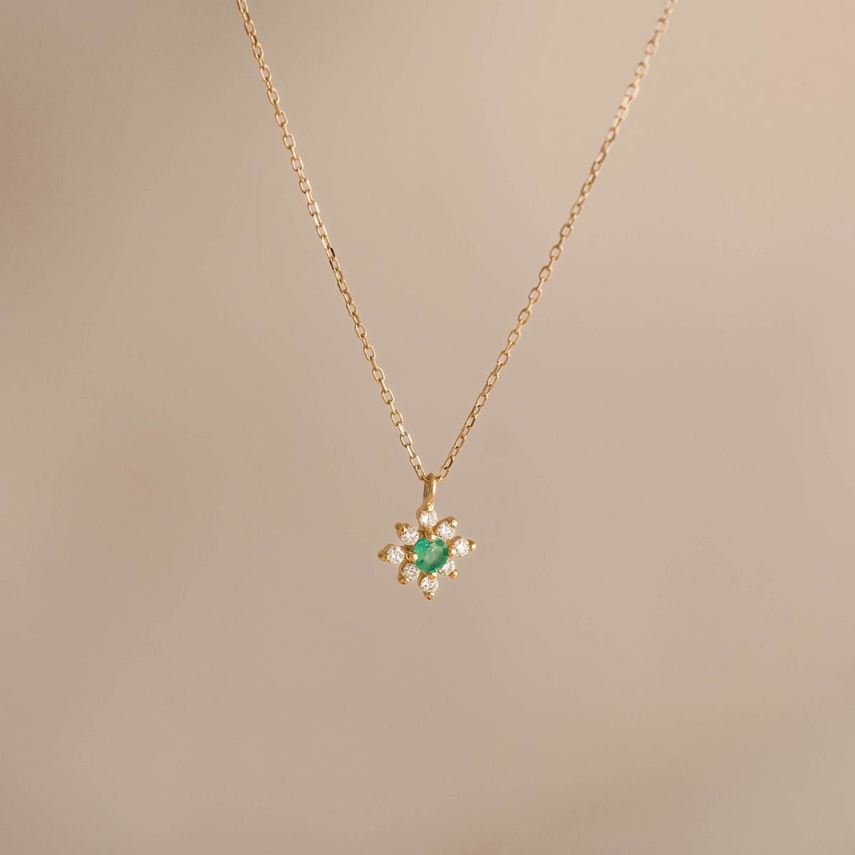 Emerald Flower Pendant Necklace 14k Gold - Inga featuring a delicate chain and emerald diamond flower pendant on beige background
