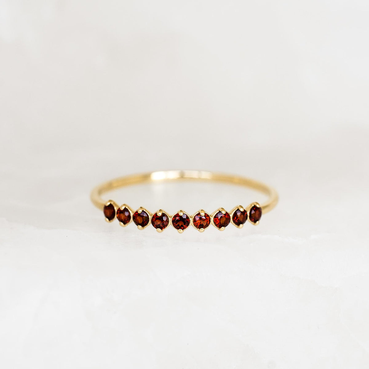 January Birthstone Ring 14k Gold - Garnet featuring nine small garnet gemstones set on a delicate gold band on white background