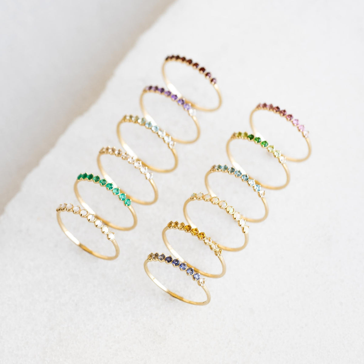 Twelve delicate December Birthstone Ring 14k Gold - Ombre Cordierite rings arranged in rows on a white surface