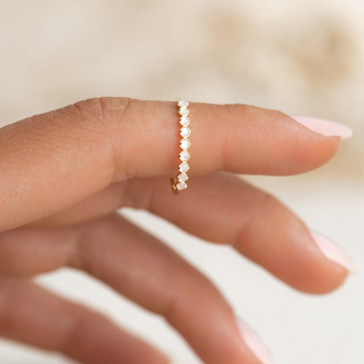 Close-up of hand wearing the June Birthstone Ring 14k Gold - Mother of Pearl with delicate pearl gemstones