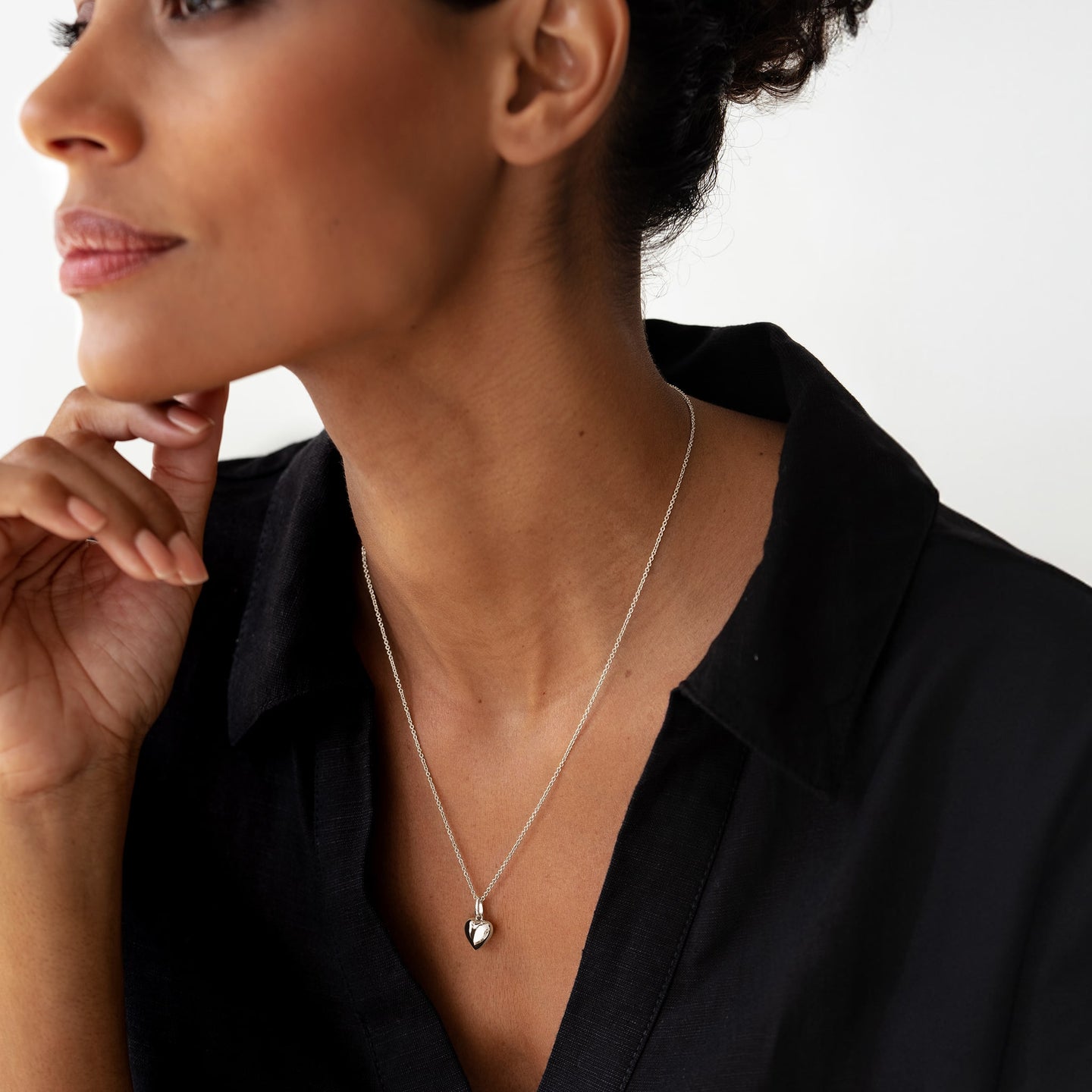 Close-up of a woman wearing the Puffy Heart Necklace Silver featuring a sterling silver heart pendant on a delicate chain