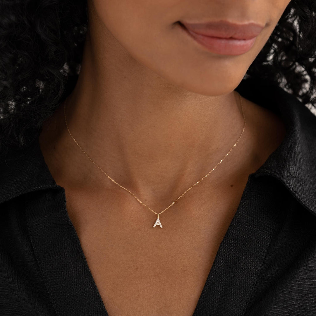 Close-up of woman wearing a Diamond Initial Pendant 14k Gold - F necklace with a black collared shirt