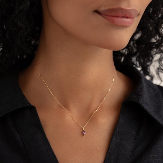 Close-up of a woman wearing the February Birthstone Pendant 14k Gold - Amethyst with a black collared shirt