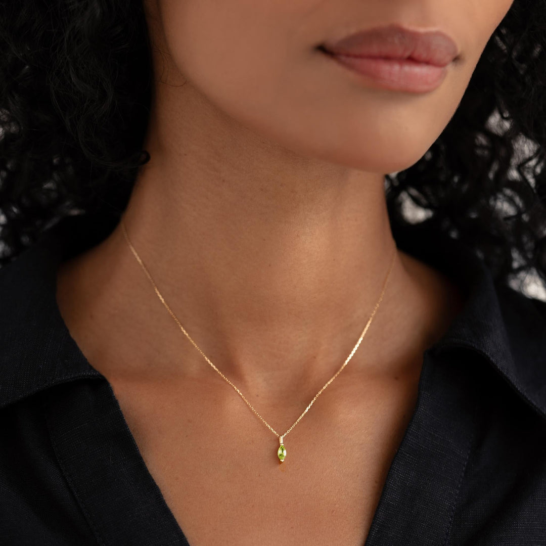 Close-up of woman wearing August Birthstone Pendant 14k Gold - Olivine on a delicate gold chain with black top