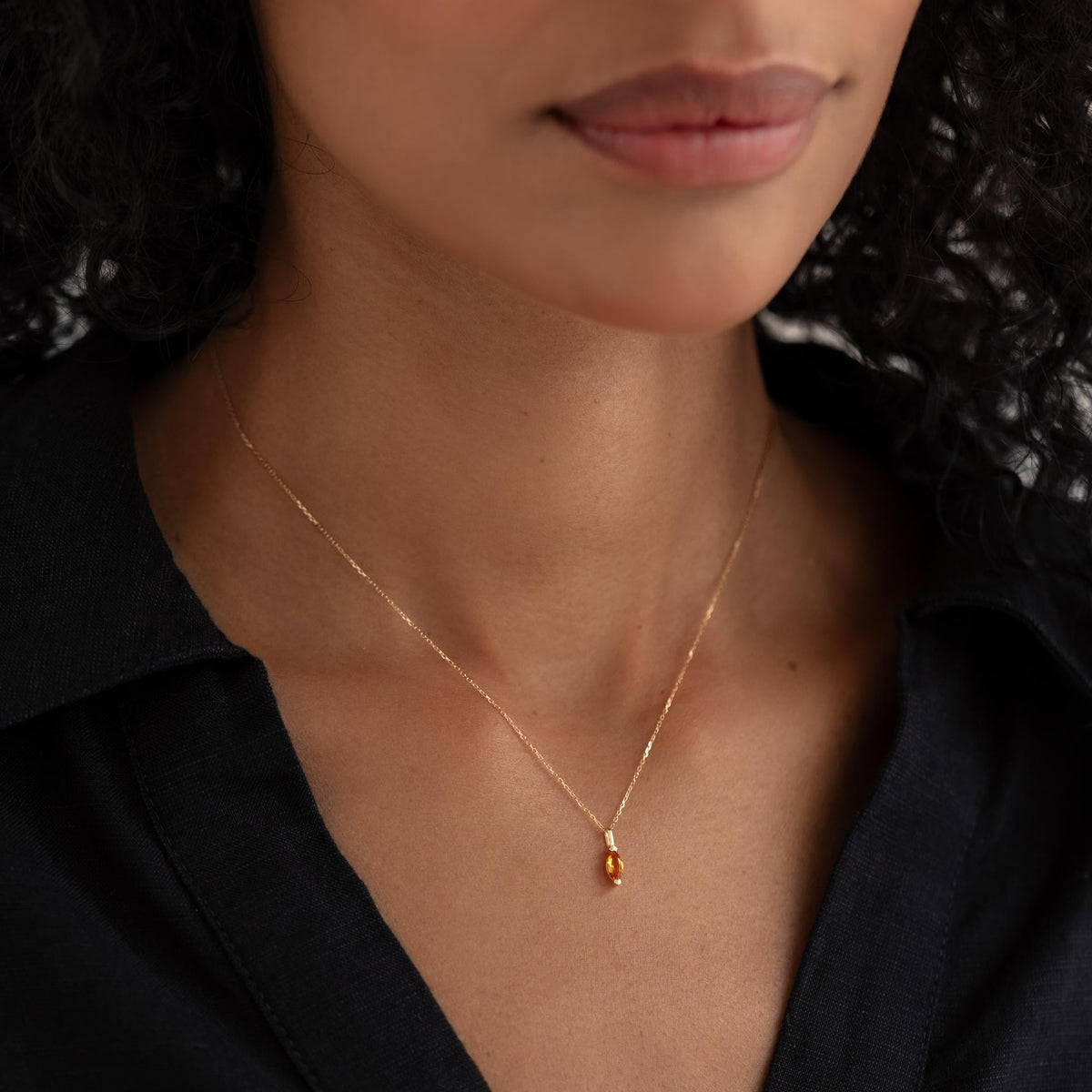 Close-up of a woman wearing the November Birthstone Pendant 14k Gold - Citrine on a delicate gold chain with black top