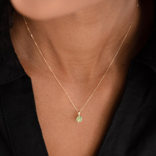 Close-up of a woman wearing the Four Leaf Clover Charm 14k Gold necklace with a black top background