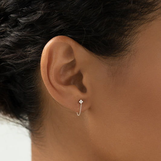 Close-up of an ear wearing Diamond Chain Earrings White Gold - Alva with delicate star design and fine chain loop