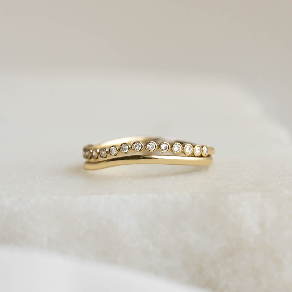 Diamond Wavy Ring 14k Gold - Amara with 16 bezel-set lab grown diamonds on a soft neutral surface