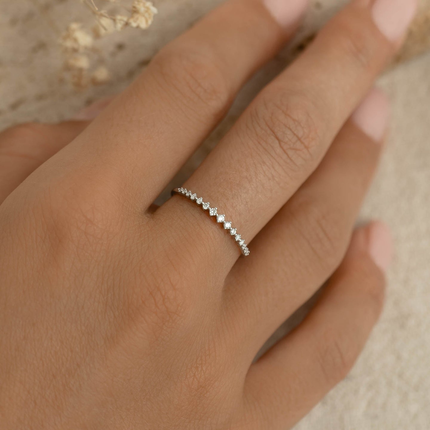 Close-up of a hand wearing the Graduated Diamond Ring White Gold - Ophelia with a row of small sparkling diamonds