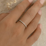 Close-up of a hand wearing the Graduated Diamond Ring White Gold - Ophelia with a row of small sparkling diamonds