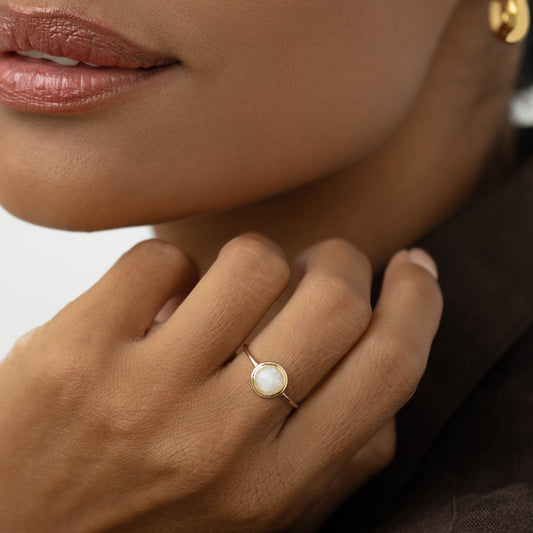Close-up of a woman wearing the Moonstone Ring 14k Gold - Zosia featuring a round rainbow moonstone on her finger
