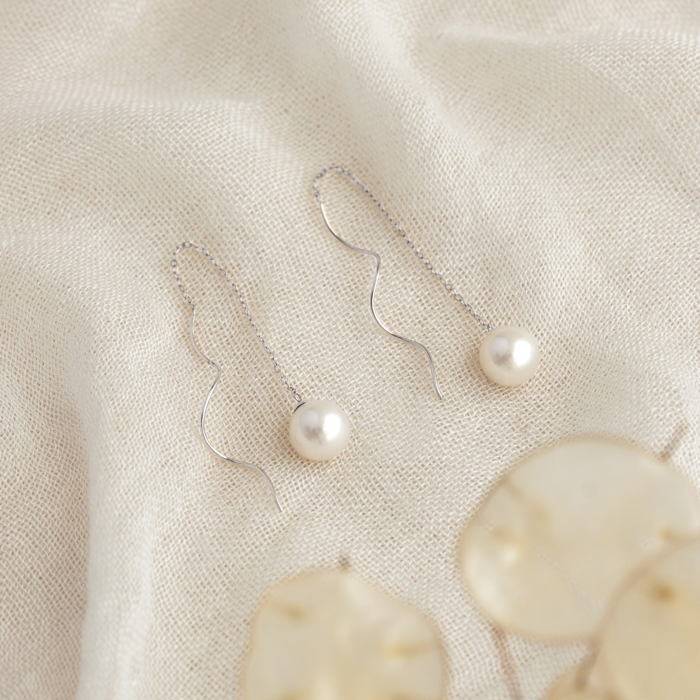 Pearl Threader Earrings White Gold - Anthea with freshwater pearls on delicate 14k white gold chains on textured fabric background
