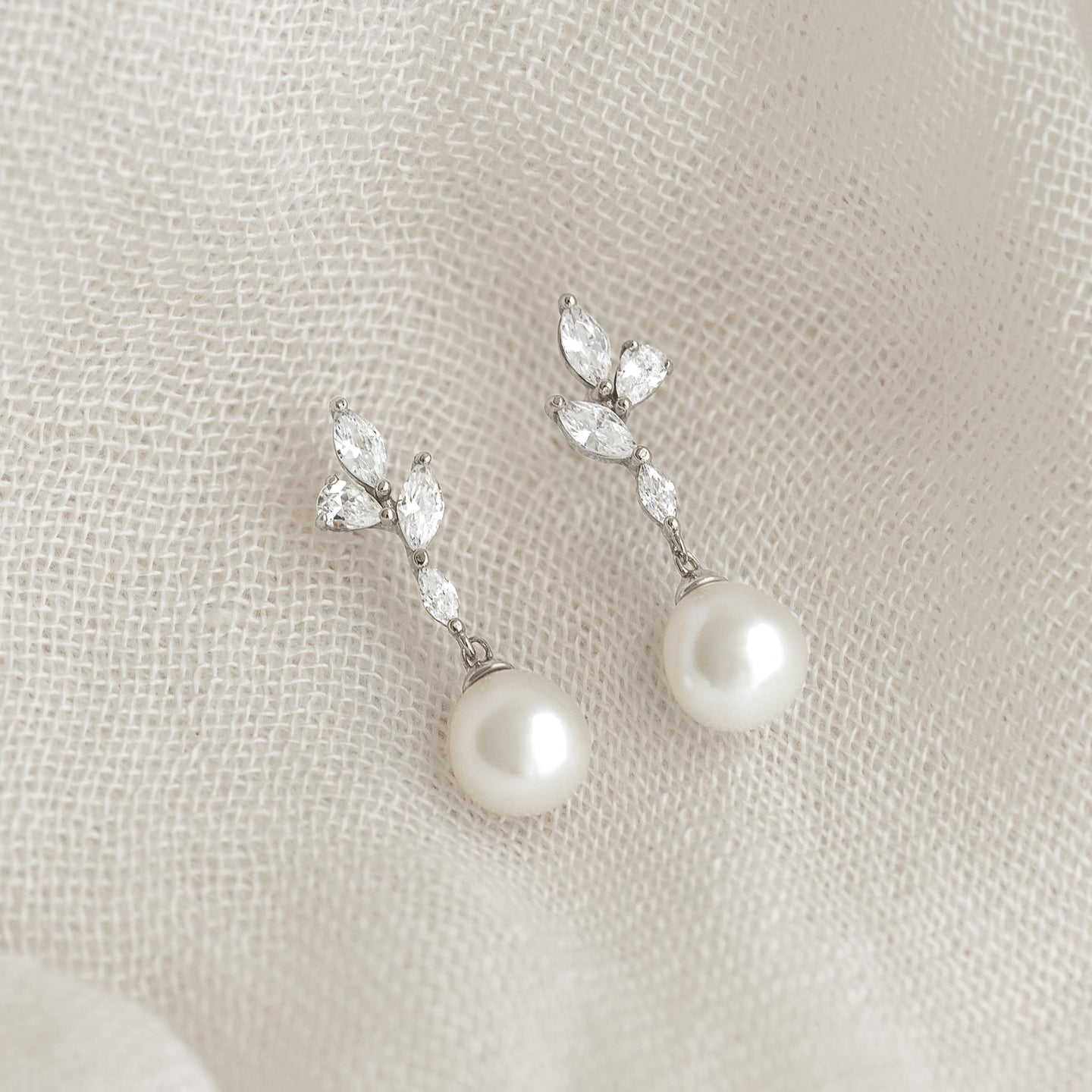 Close-up of Pearl Drop Earrings Silver - Ariana featuring baroque pearls and cubic zirconia on a textured fabric background