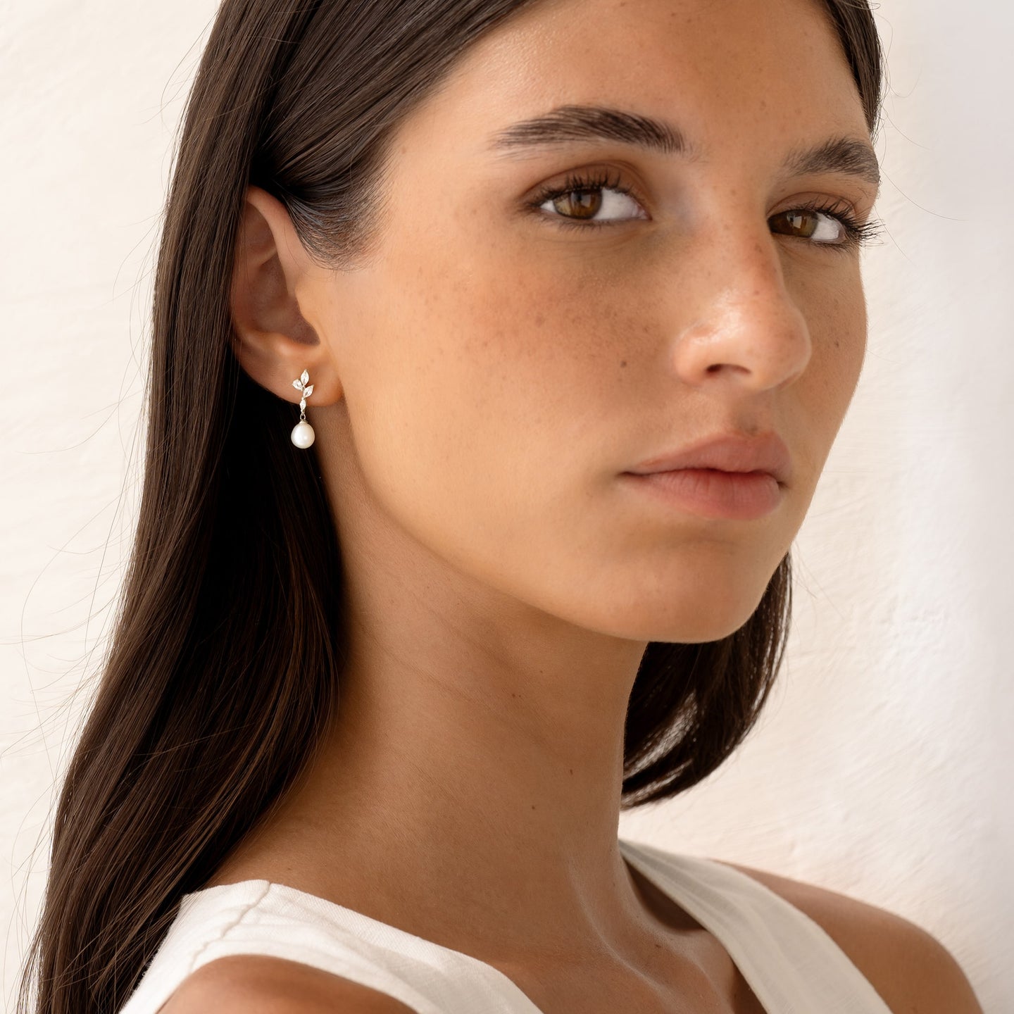 Close-up of a woman wearing Pearl Drop Earrings Silver - Ariana with baroque pearls and cubic zirconia on a white background