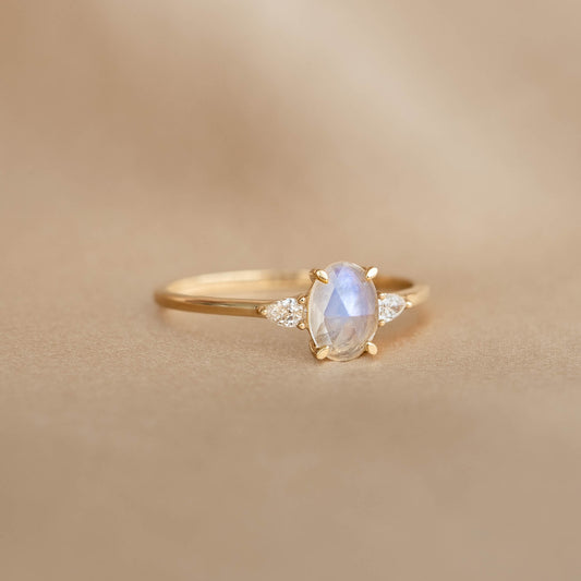 Close-up of Moonstone and Diamond Ring 14k Gold - Maia with oval moonstone and two small diamonds on a neutral background