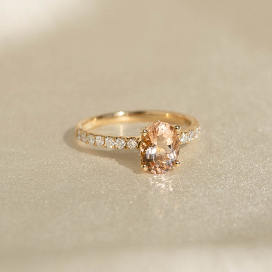 Close-up of Oval Morganite and Diamond Ring 14k Gold - Minette with pavé diamonds on a soft beige surface