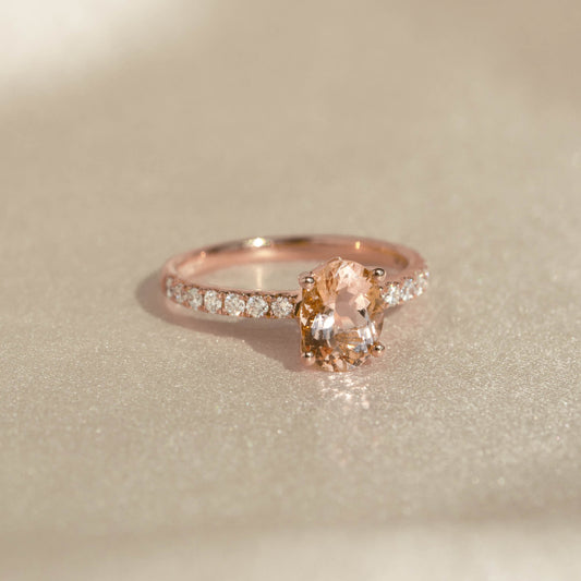 Close-up of Oval Morganite and Diamond Ring Rose Gold - Minette with oval morganite and pavé diamonds on a soft beige surface