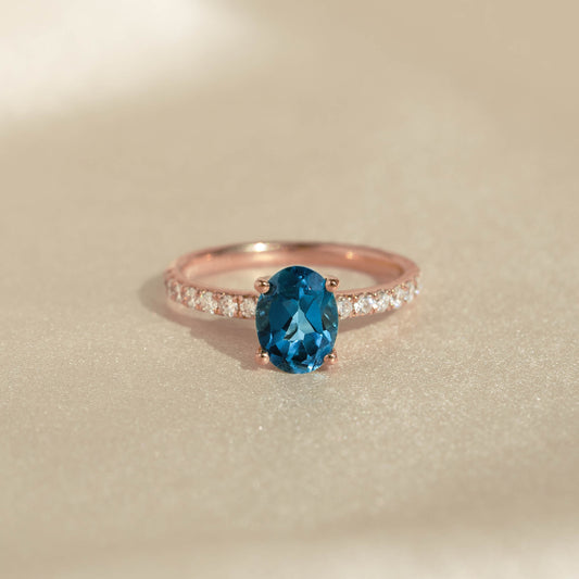 Oval London Blue Topaz and Diamond Ring Rose Gold - Minette with pavé diamonds on band on soft beige background