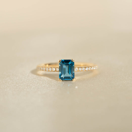 Close-up of Baguette London Blue Topaz and Diamond Ring 14k Gold - Safiya with blue topaz and pavé diamond band on neutral background