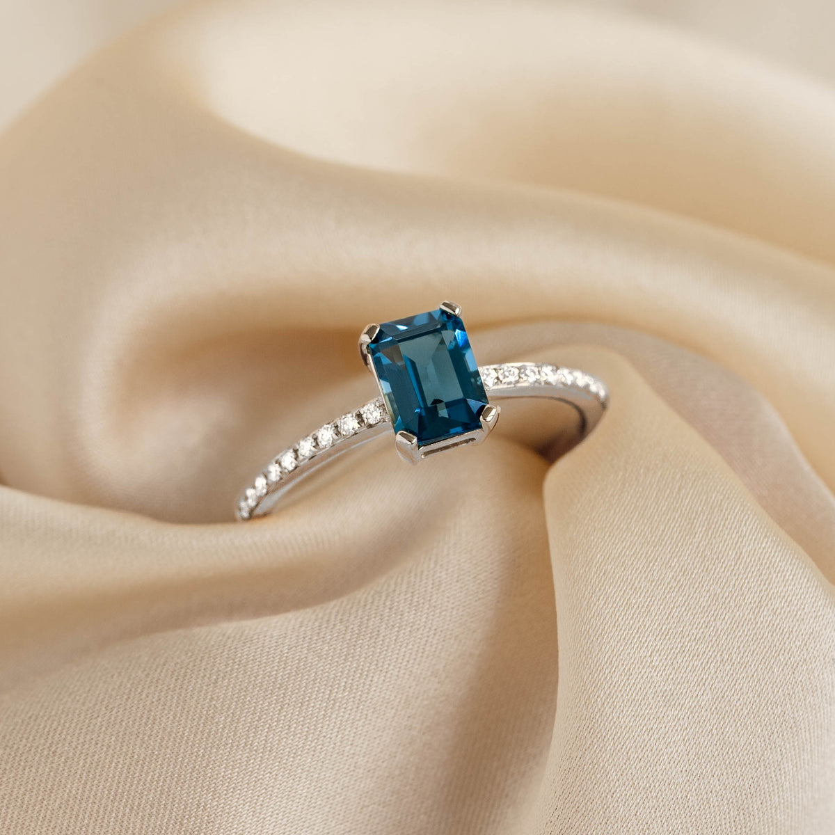 Baguette London Blue Topaz and Diamond Ring White Gold - Safiya with rectangular blue topaz and diamond set band on beige fabric