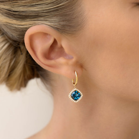 Close-up of a woman wearing London Blue Topaz and Diamond Halo Drop Earrings 14k Gold - Elvira on a neutral background