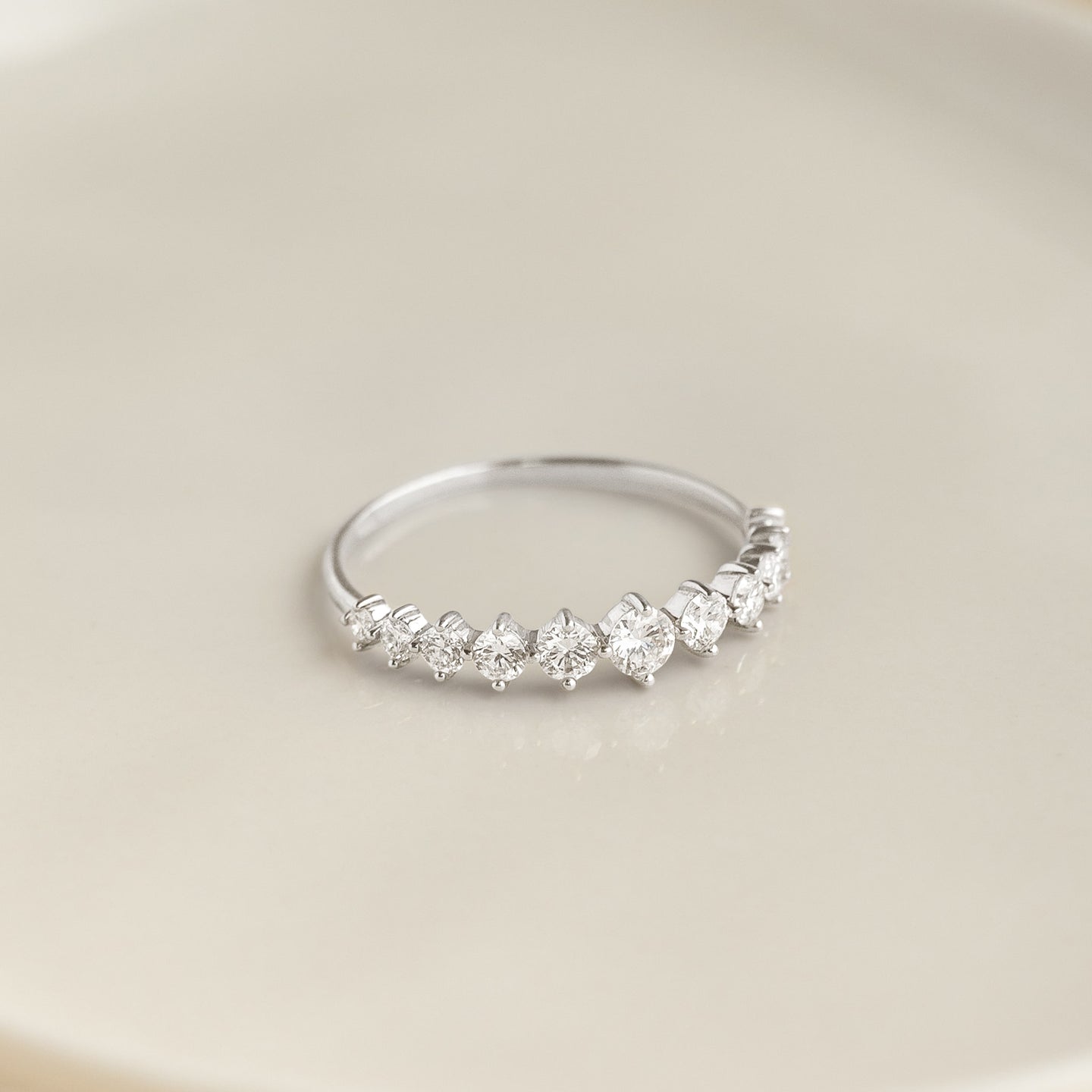 Close-up of the Graduated Diamond Ring White Gold - Giselle with 11 brilliant diamonds on 14k white gold band on a neutral background