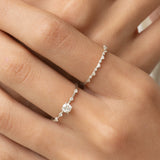 Close-up of a hand wearing the Round Diamond Ring White Gold - Rocio with a round diamond center stone and side diamonds