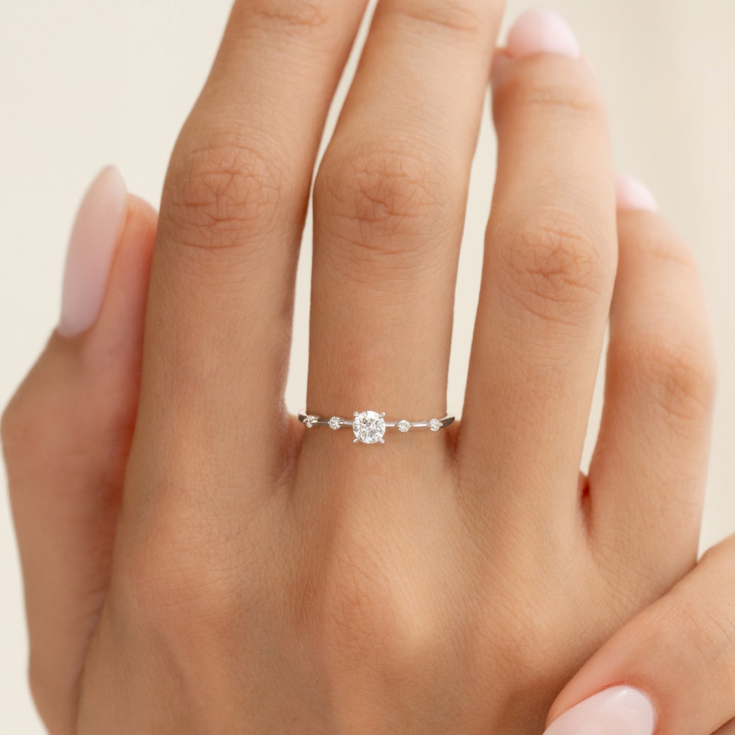 Close-up of a hand wearing the Round Diamond Ring White Gold - Rocio with a sparkling round center diamond and side accents