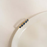 Sapphire Half Eternity Ring 14k Gold - Capriana with pear-cut blue sapphires on a white curved surface