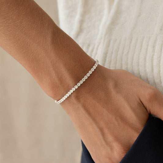 Close-up of a hand wearing the Tennis Bracelet Silver - Zilla with round cubic zirconia stones on a neutral background