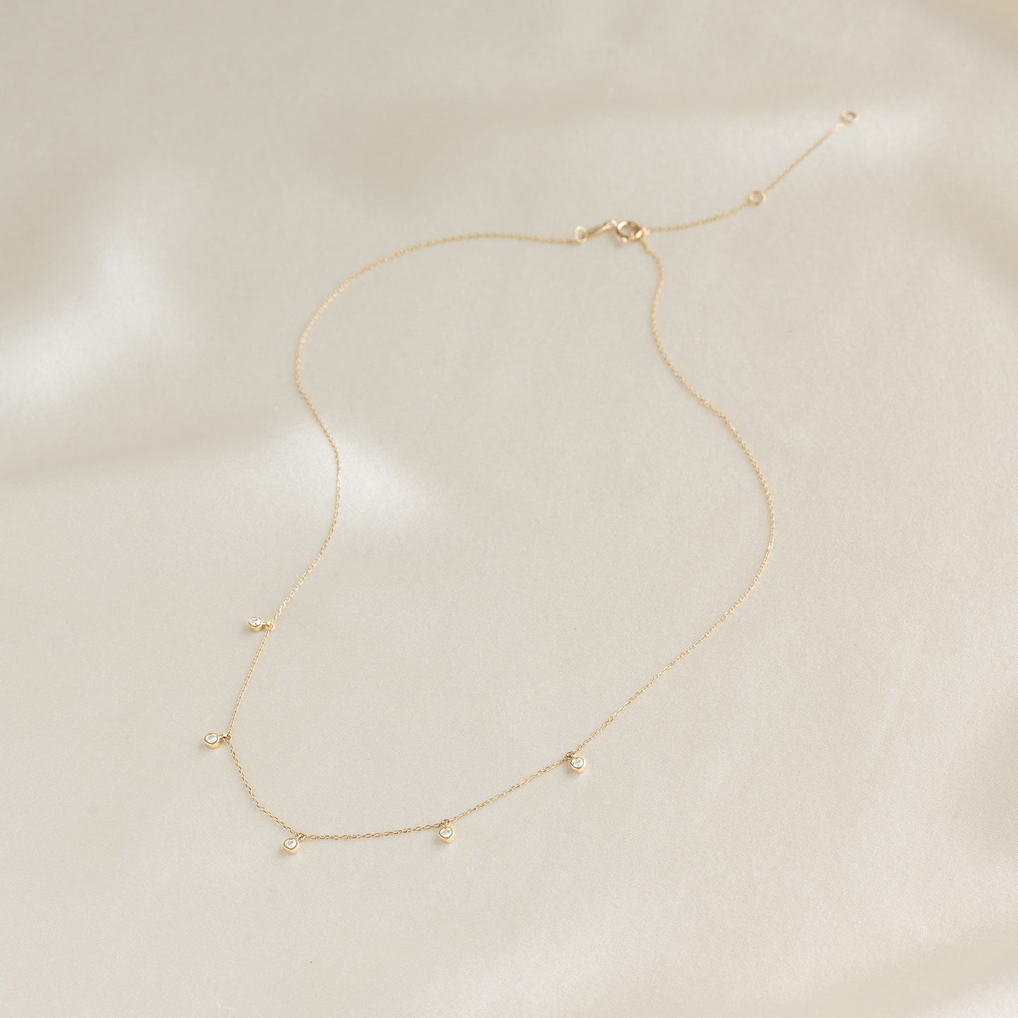 5-Diamond Necklace 14k Gold - Bette featuring five bezel-set diamonds on a delicate gold chain on a soft background