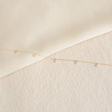 Delicate 5-Diamond Necklace 14k Gold - Bette with five bezel-set diamonds on a fine gold chain on textured background
