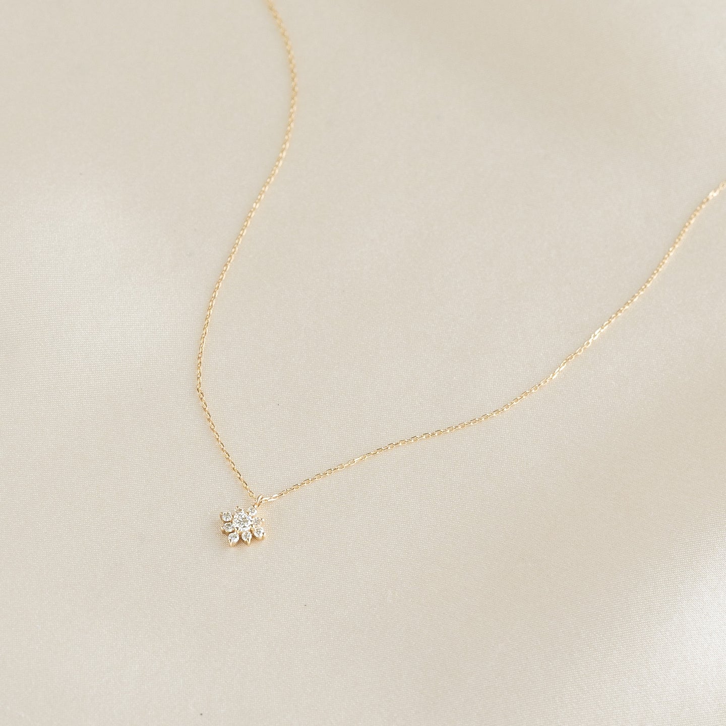 Delicate Flower Diamond Pendant Necklace 14k Gold - Fiorella with nine sparkling diamonds on fine gold chain on cream background