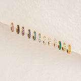 Row of gold vermeil huggie earrings with various colored gemstones including September Birthstone Huggie Earrings - London Blue Topaz