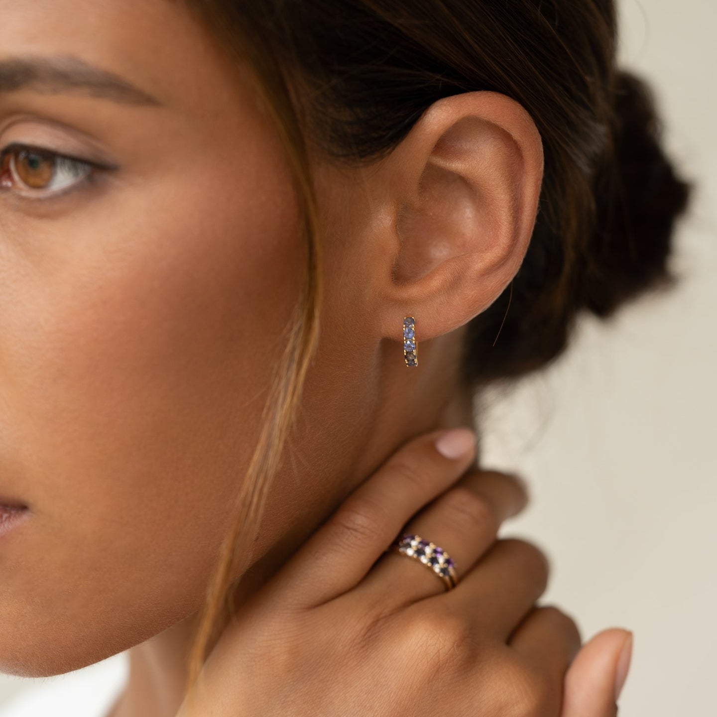 Close-up of a woman wearing December Birthstone Huggie Earrings - Cordierite with gold vermeil setting and matching ring
