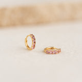 Close-up of July Birthstone Huggie Earrings - Pink Tourmaline with gold vermeil setting on neutral background