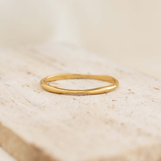 Close-up of Gold Organic Bangle S - Aelia with a molten asymmetrical shape on a textured beige surface