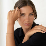 Woman wearing Diamond Tennis Bracelet 14k Gold (1.501 ct tw) - Mirella with rings and black top against white background