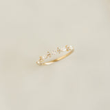 Close-up of Marquise and Round Diamond Ring - Aurelia with 14k yellow gold band on a soft beige background