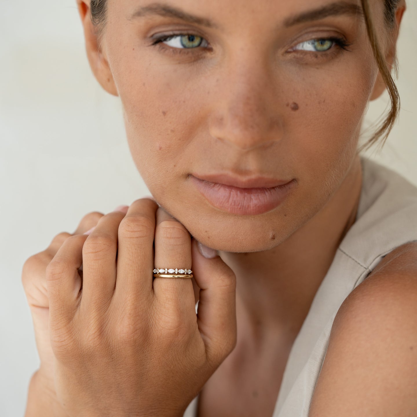 Close-up of a woman wearing the Marquise and Round Diamond Ring - Aurelia on her hand against a neutral background